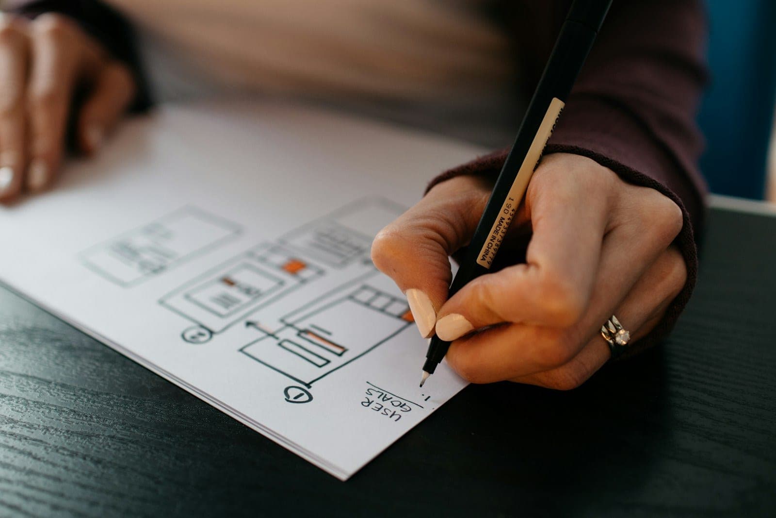 Designer sketching wireframes on paper with a pen