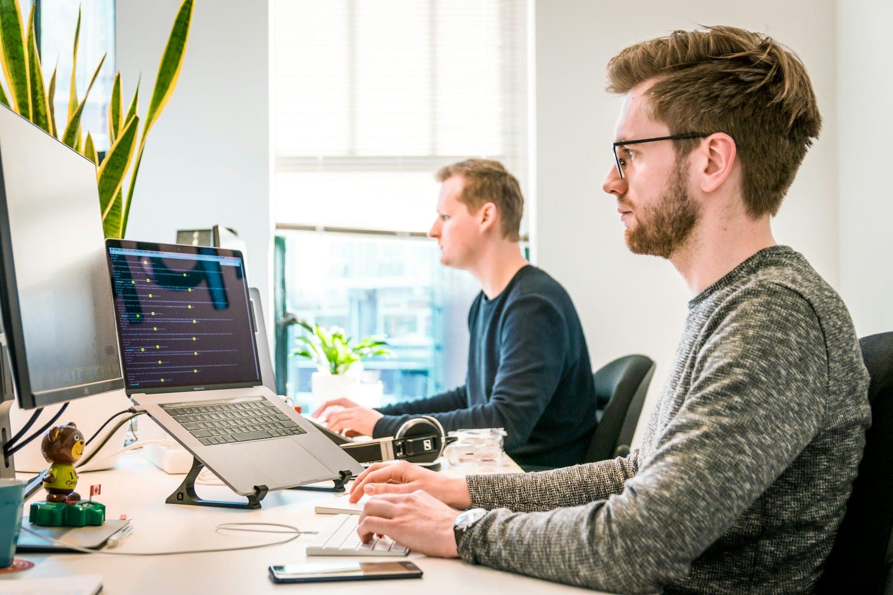 Two people working at desks with monitors in a bright studio