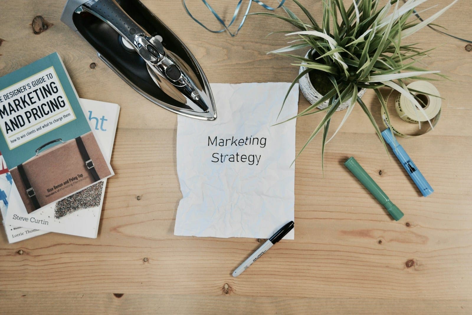 Desk with notebooks, a marketing book and a plant