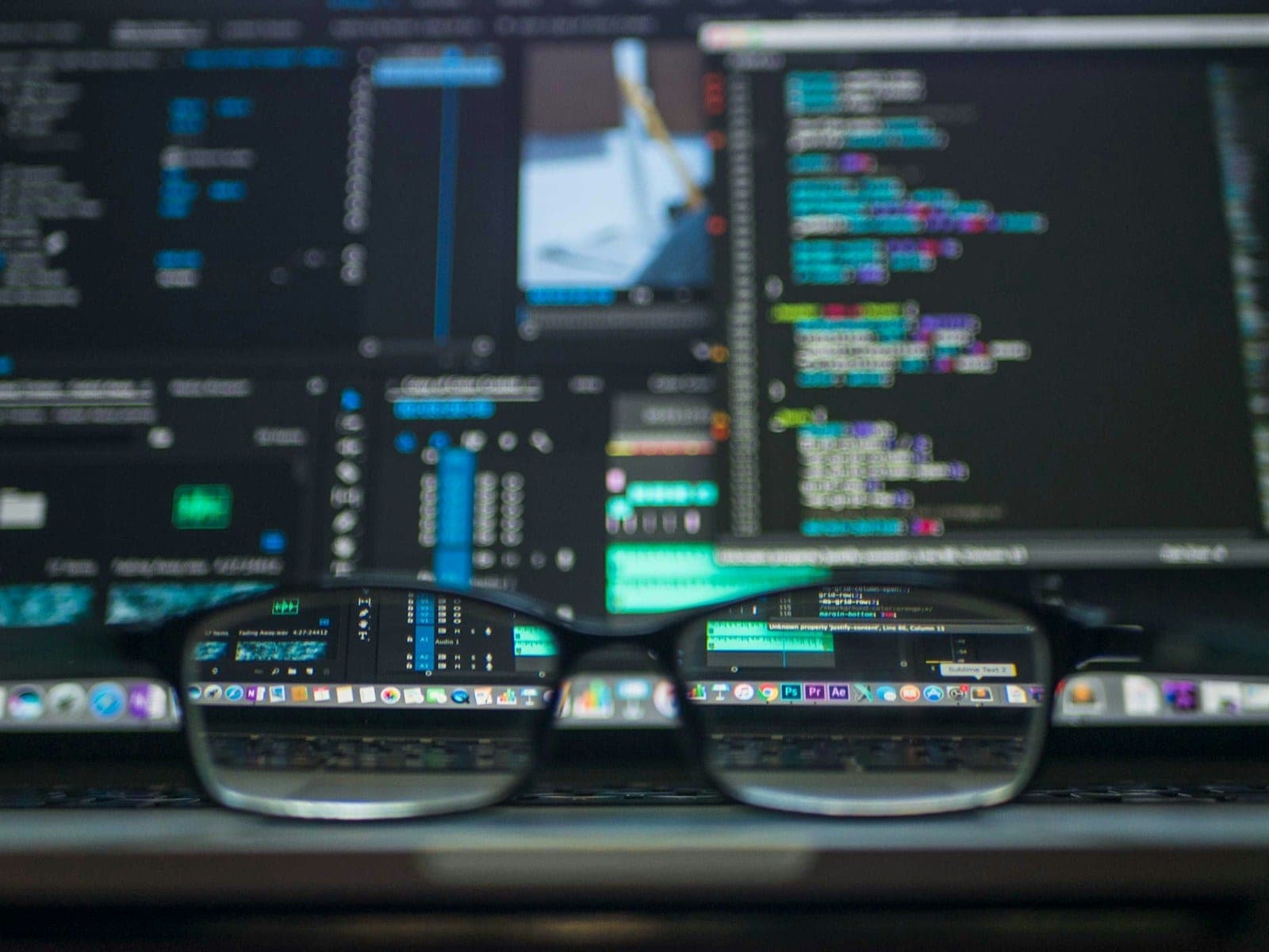 Monitor with code and a pair of glasses in front of it